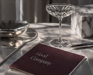 A burgundy notebook beside a crystal coupe on a marble table.