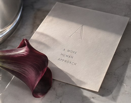 An embossed card on marble beside a burgundy calla lily.