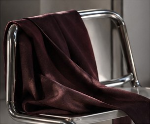 A burgundy silk scarf draped over a chrome chair.